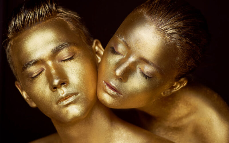 Male and female face around. The woman's head lies on the shoulder of a man. All painted in gold paint, the feeling of a single whole organism.